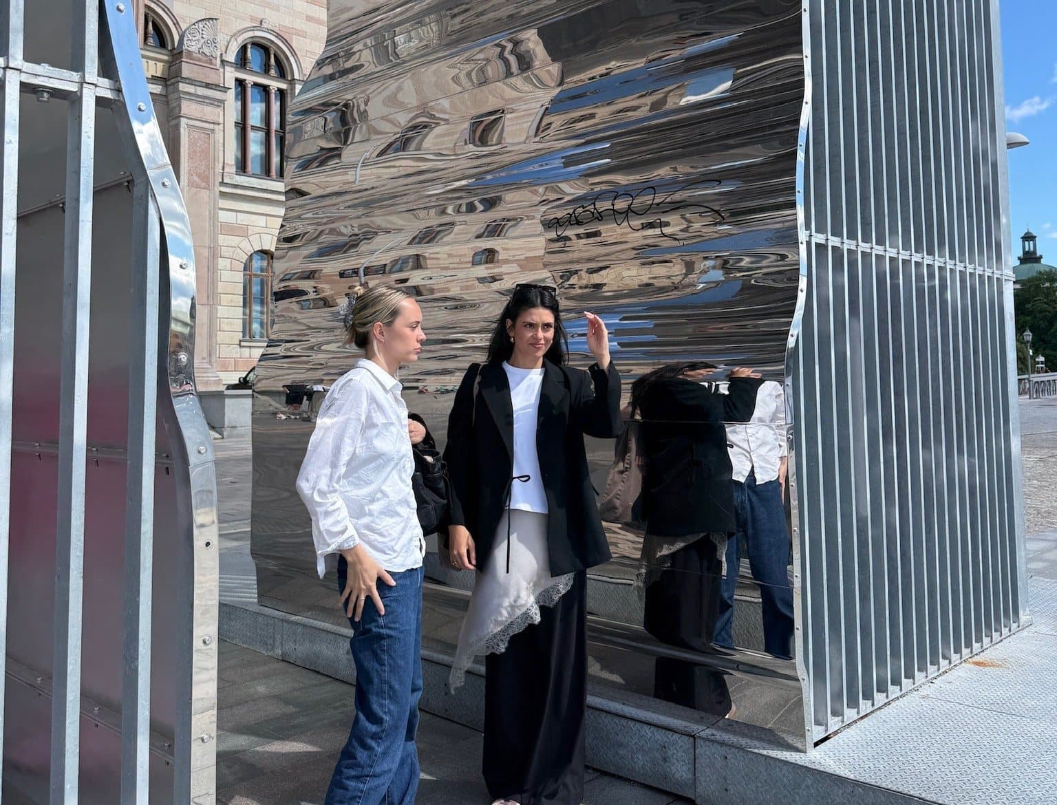 Lucia and Freya in front of a mirrored sculpture in Stockholm