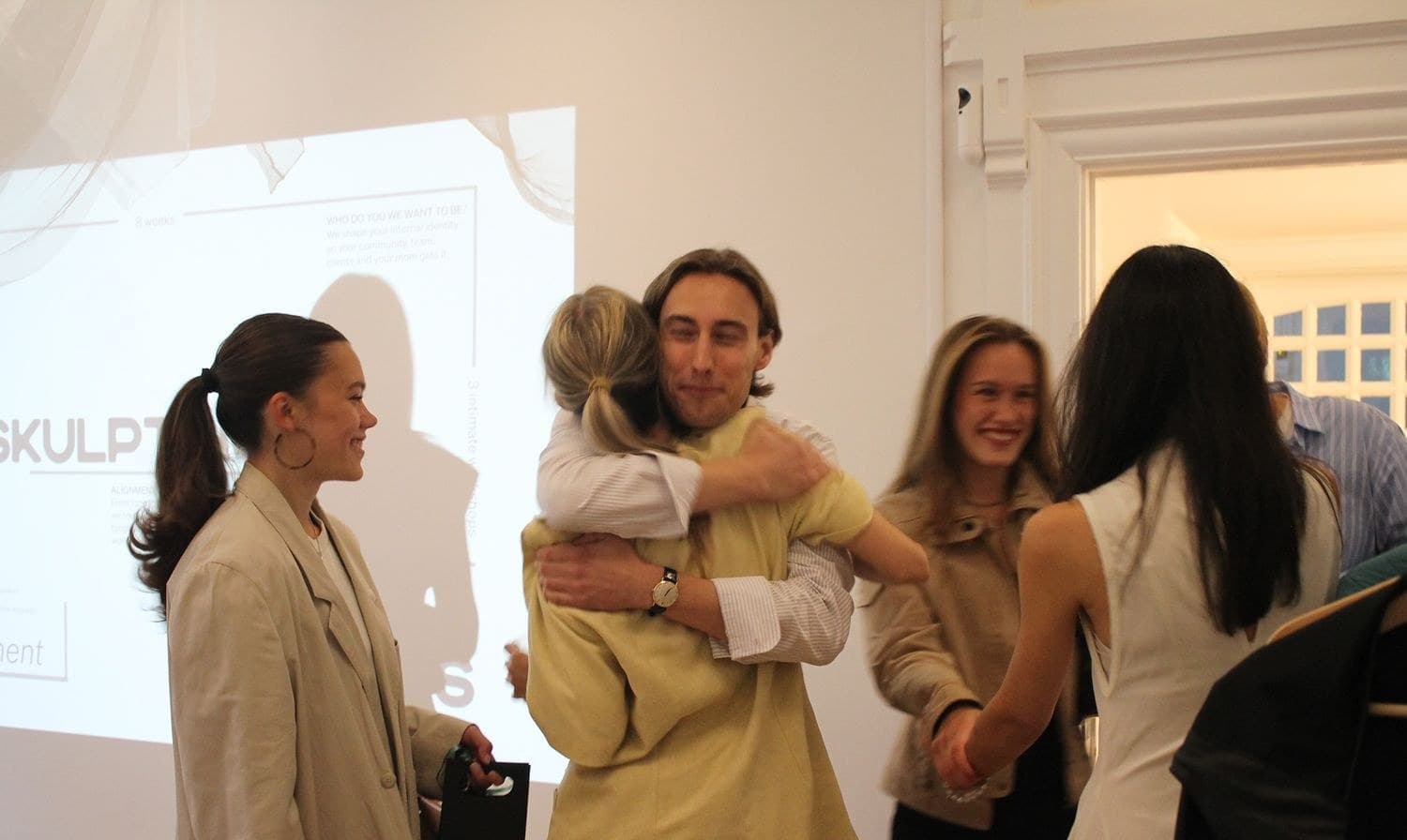 Founders hugging in front of a projection at a SKULPT event