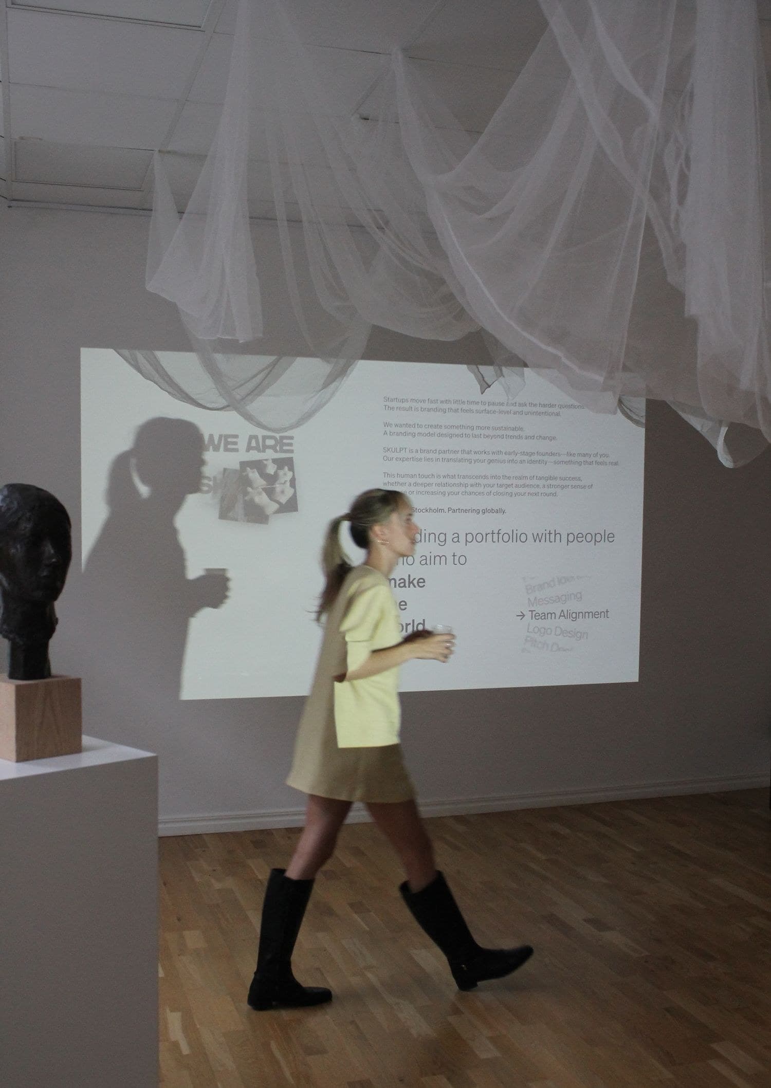 Guest walking past a projected presentation at a SKULPT event